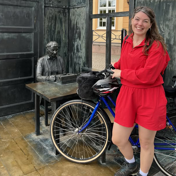 Caroline Cabot med en cykel framför Astrid Lindgrens staty på Vimmerby torg.